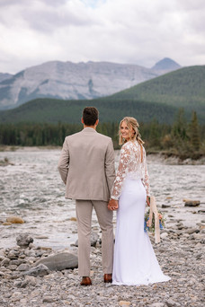 Bride looking back while standing with her groom, facing the mountains before their Kananaskis wedding
