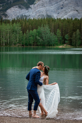 Bride and groom kissing in front of the water in Kananaskis.