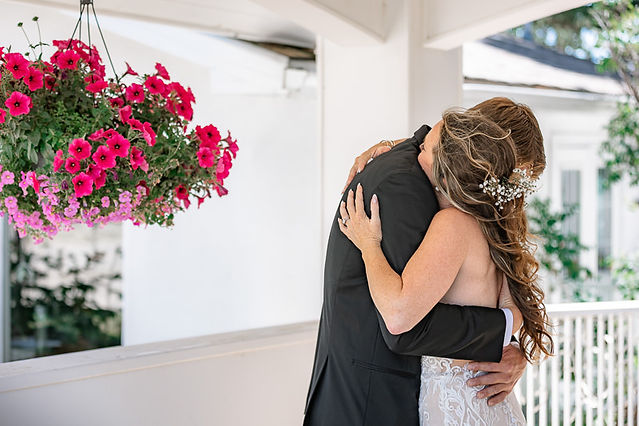 Bride and groom sharing an emotional hug during their first look on a covered walkway at a Cochrane wedding venue.