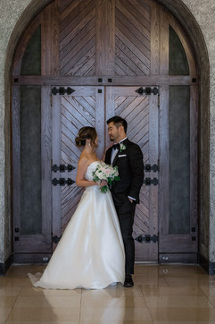 Bride and groom look at each other and smile infront of doors