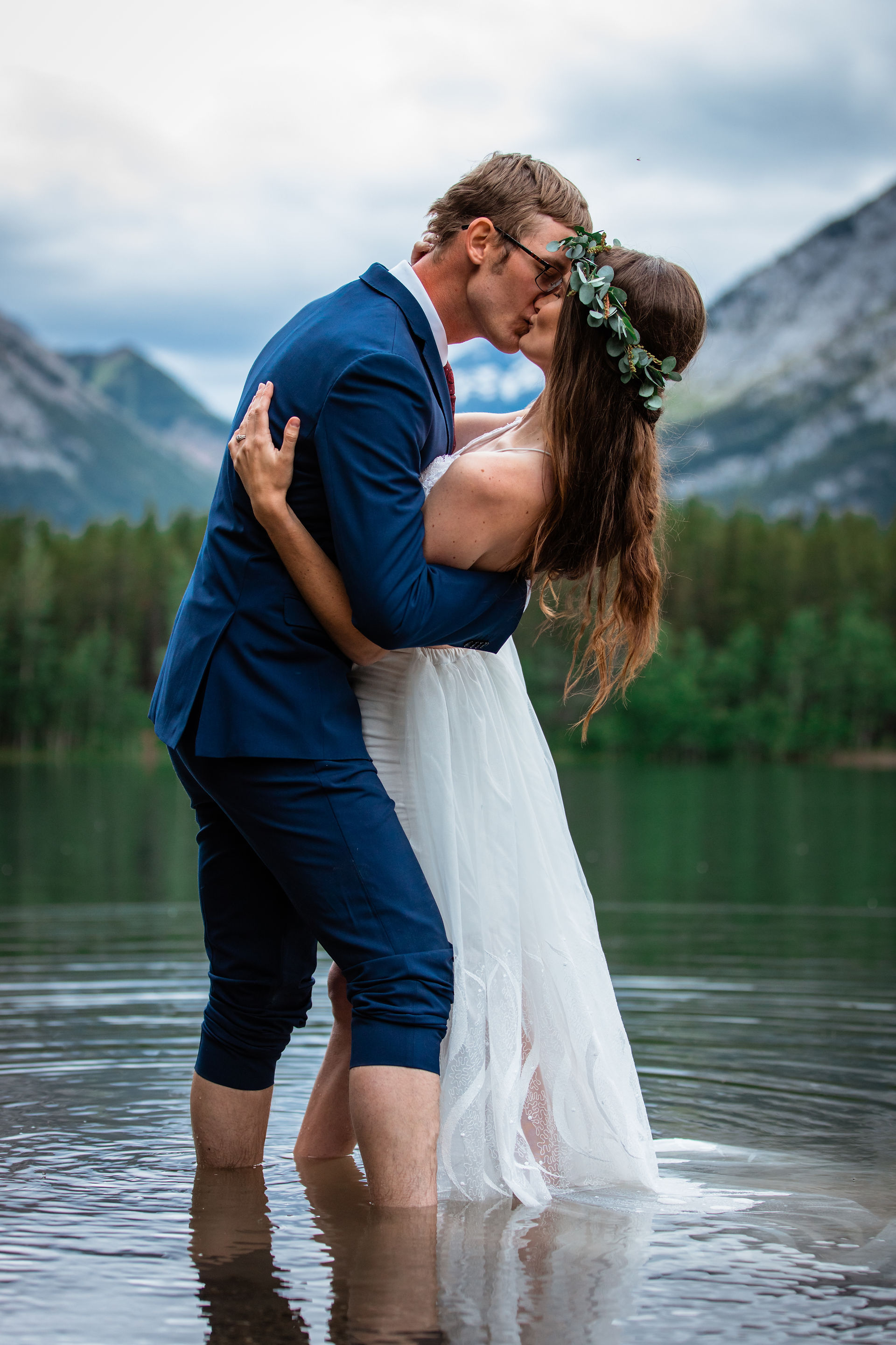 Bride and groom embracing in front of the water in Kananaskis.