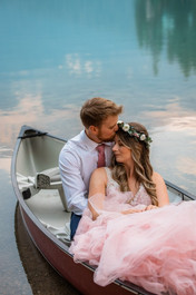 Groom kisses bride on head in canoe