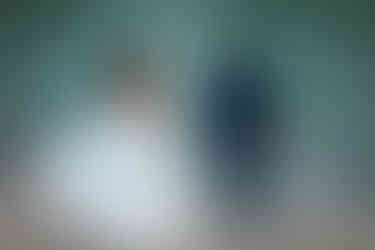 Bride and groom posing in front of the water in Kananaskis. Couple is looking at the water and the brides dress in flowing in the wind.