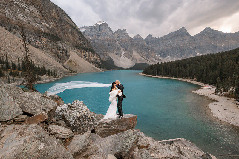 Bride and groom sharing a quiet moment during their Moraine Lake wedding with family surrounded by the breathtaking Canadian Rockies.