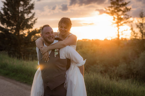 groom giving bride a piggy back at sunset