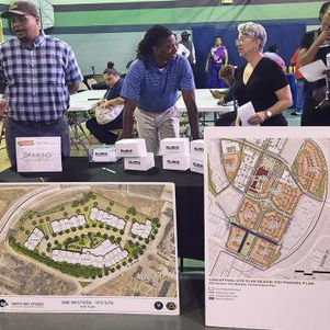 Residents walk around a job fair with tables and posters displaying the redevelopment plans.