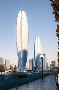 Rendering of two sleek, modern, curved skyscrapers dominate a bright city skyline.