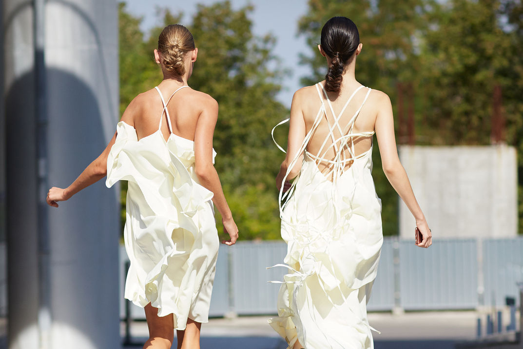 Mellow Yellow to young women wearing yellow light weight summer dresses which move fluidly as they run away from camera.