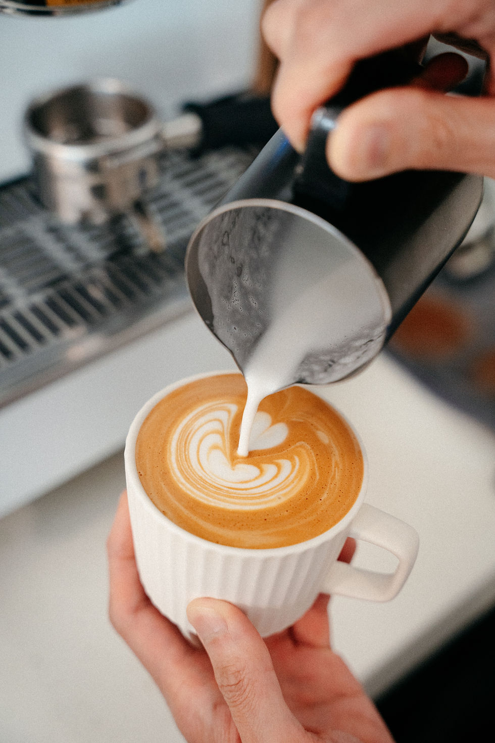 barista pouring latte art into a coffee cup