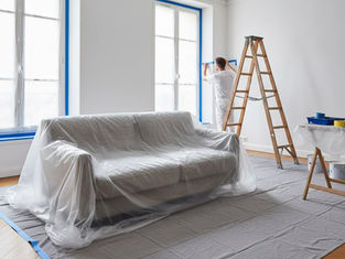 Protection minutieuse du sol et des meubles avec des bâches et du ruban de masquage avant travaux.