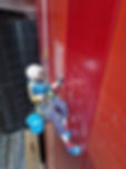 A worker in safety gear hangs from ropes, scaling a tall building to install side of the window