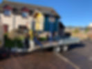 A colourful playhouse, painted blue and yellow, is strapped onto a trailer