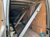 The interior of a van with wooden panels, holding two large window frames