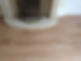 A wooden floor in front of a stone fireplace