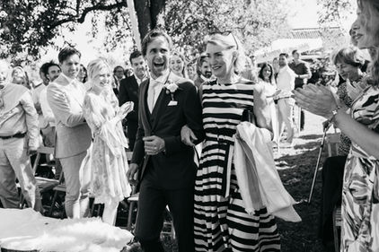 Documentaire trouwfoto waar de moeder de bruidegom naar het altaar brengt met daaromheen klappende gasten