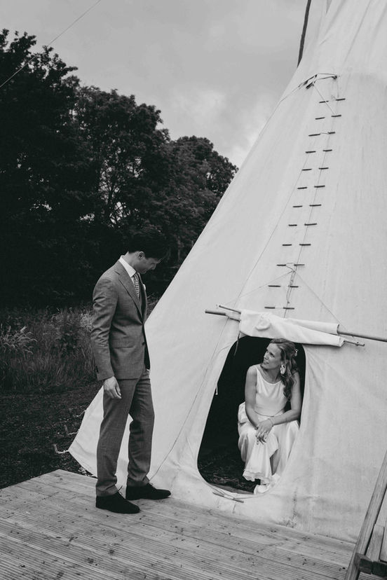 bruidspaar voor witte tipi tent bij trouwlocatie het Verre Oosten 