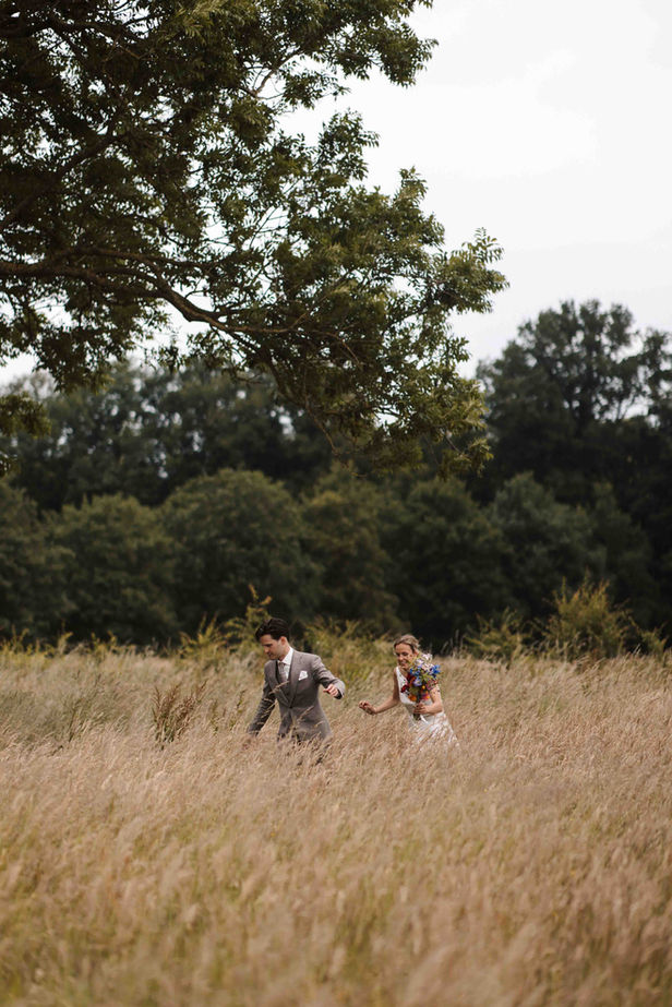 bruidspaar lachend in weiland met hoog gras