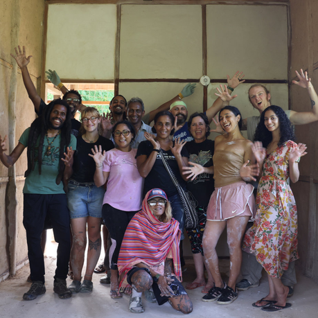 Participants celebrating infront of a naturally plastered wall at Earth Building Immersion