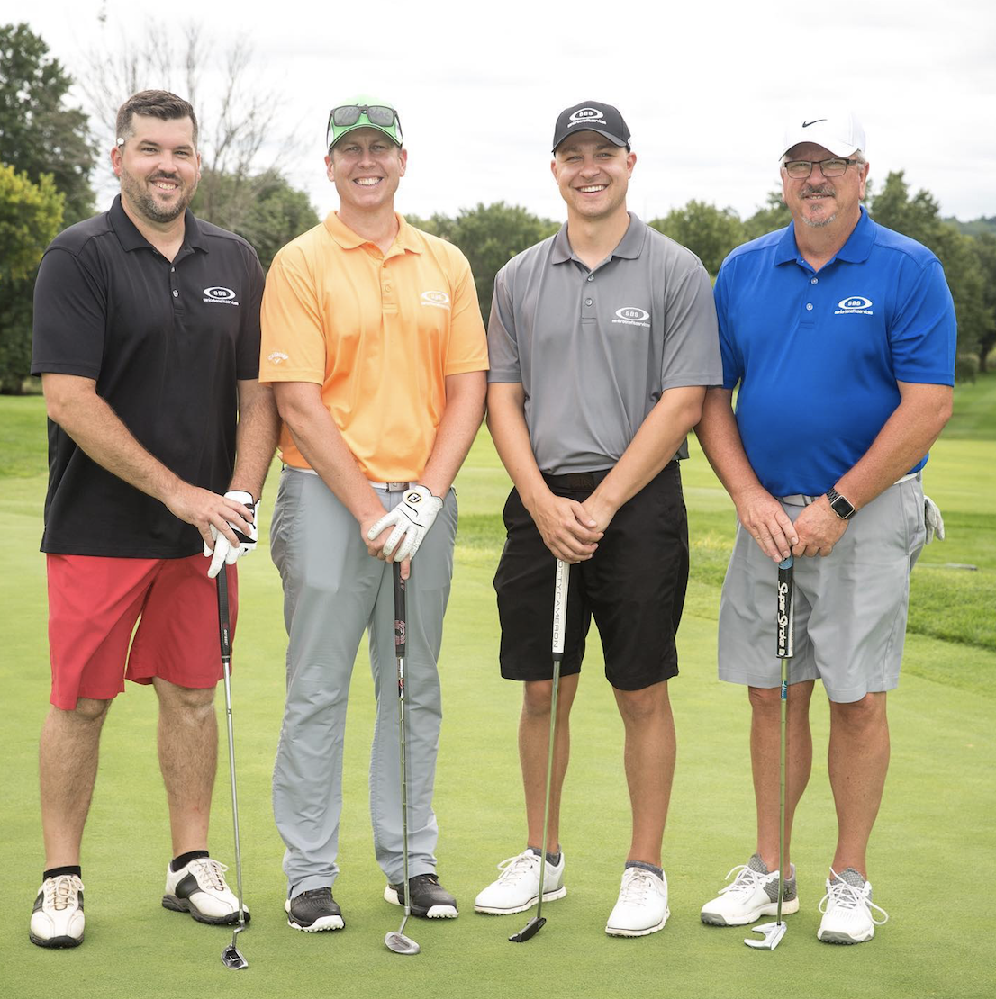 Medium shot of 4 Senior Benefit Services Employees lined up at a golf course.