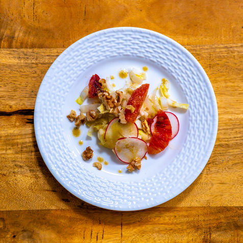 Fine dining plated dish on white porcelain photographed from above on natural wood surface
