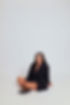 Smiling woman in a black blazer sitting cross-legged