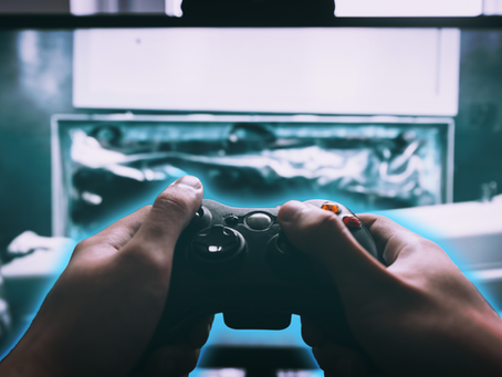 Hands holding a game controller in front of a glowing game screen, illustrating the connection between visual design and gameplay mechanics in modern game development.