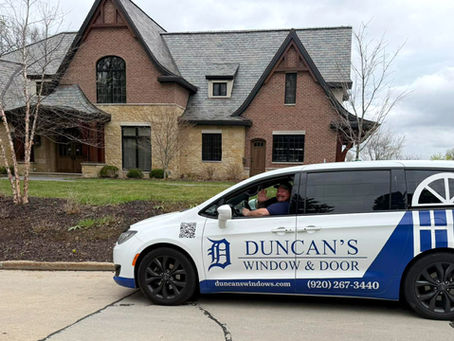 Jeremy The Window Guy is waving from his Duncan's Window & Door Mini Van. He is parked outside of a customer's home.