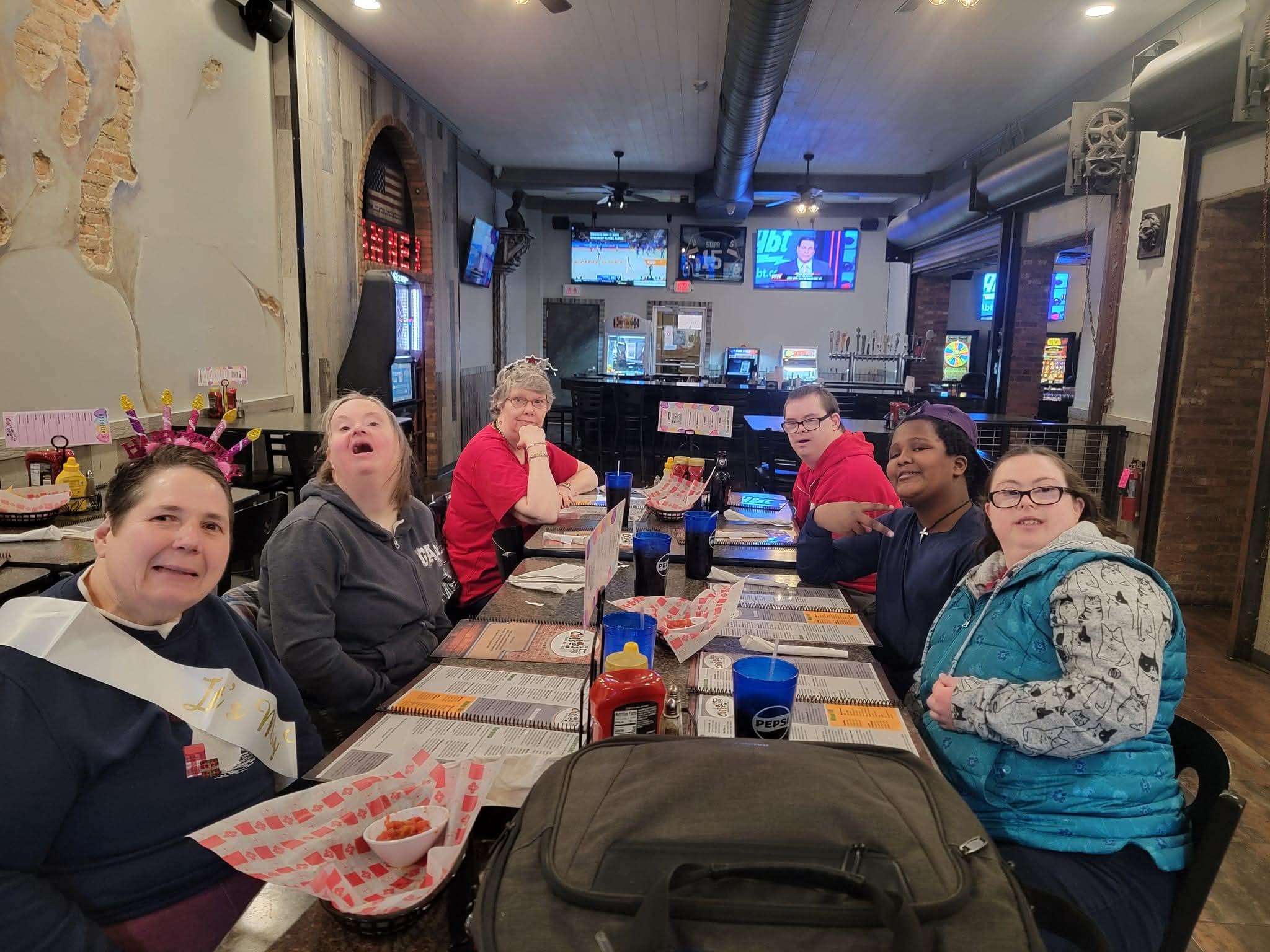 Long table with people seated and smiling on either side.