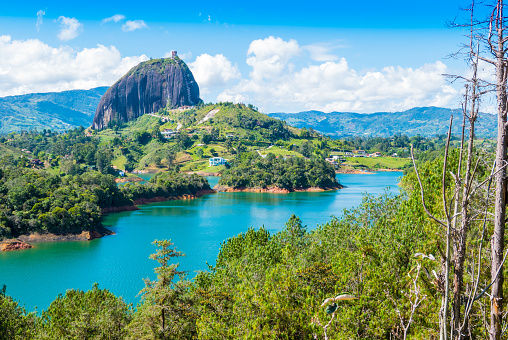 Vista panorámica de la icónica Piedra del Peñol en Guatapé, con el lago resplandeciente a su alrededor bajo un cielo despejado.