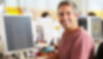 Man sitting at computer desk smiling at camera