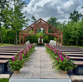 luxurious outdoor West Virginia ceremony site with stone path, benches and ferns with pink flowers. Large wooden open-air chapel at end of path located in Fayette County, WV