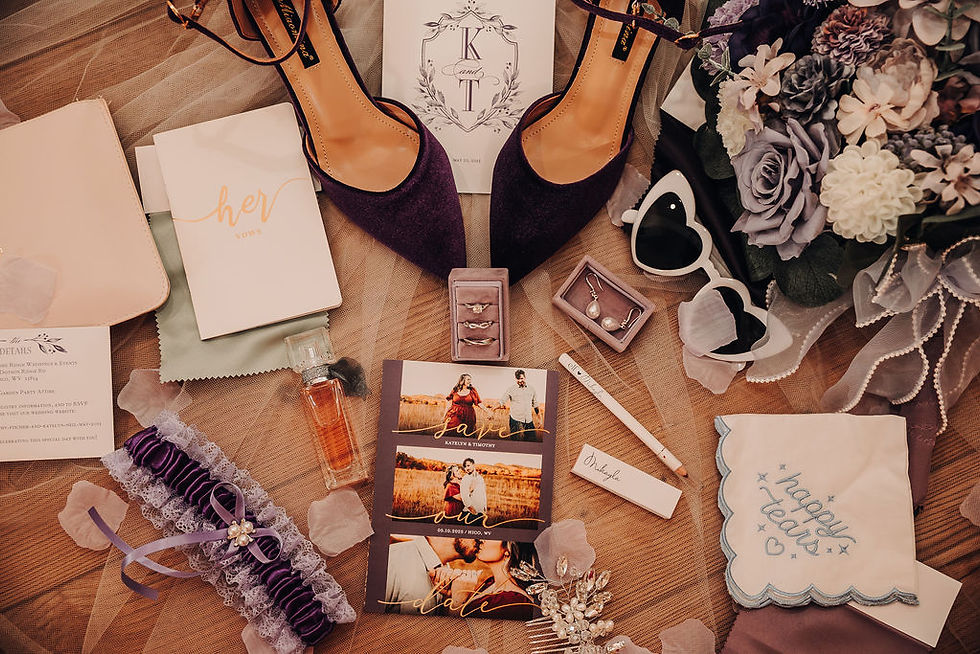 Wedding flat lay with purple shoes, bouquet, heart sunglasses, "her vows" booklet, jewelry, photos, garter, perfume, and "happy tears" tissue at Charleston, West Virginia wedding venue.