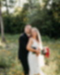 bride and groom stand smiling while surrounded by wildflowers at luxurious West Virginia wedding venue