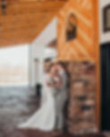 Bride and groom stand against stone fireplace smiling at each other at Charleston, West Virginia wedding venue