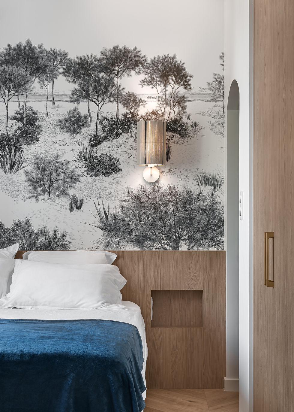 Chambre avec papier peint panoramique forêt et applique murale.