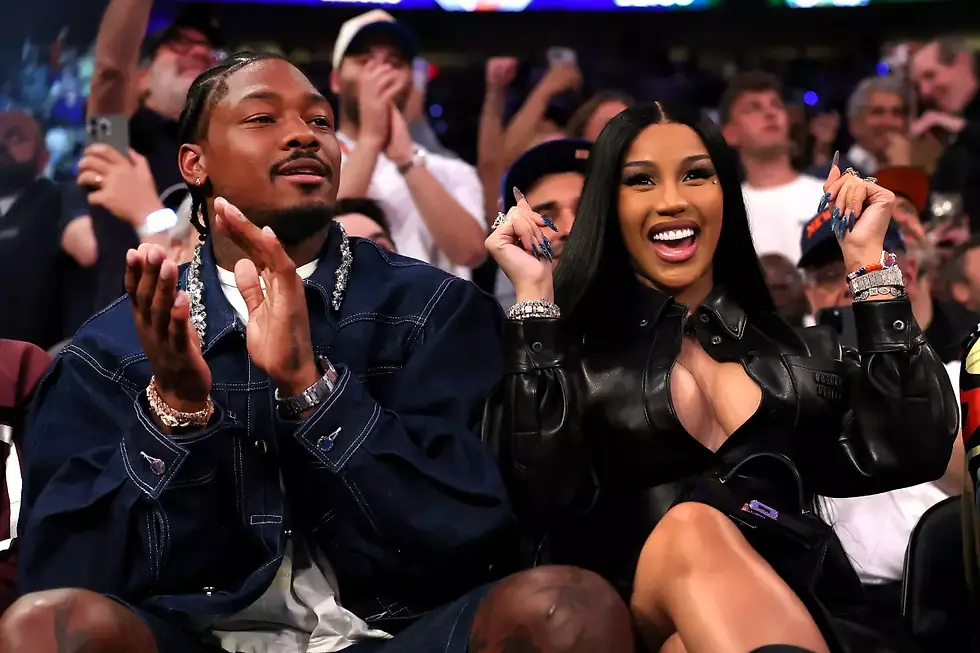 Stefon Diggs and Cardi B are in the crowd of an event, smiling. and celebrating