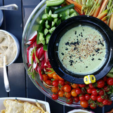 a plate of colourful vegetables arranged around a green dip