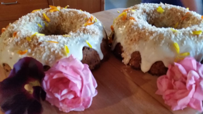Two bundt cakes with drizzled white frosting and pink roses