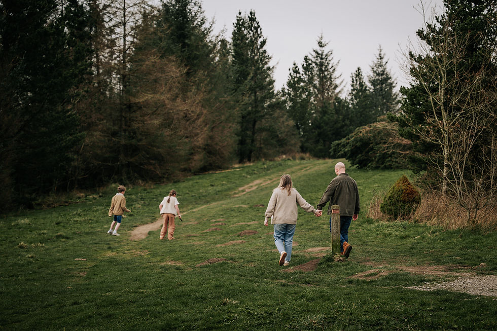 Family walking hand in hand through a lush green forest path, surrounded by tall trees, with a calm and peaceful atmosphere.
