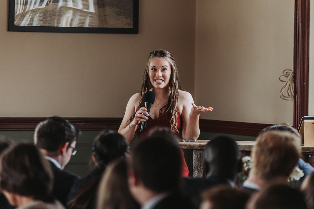 Girl giving speech in front of audience at wedding.