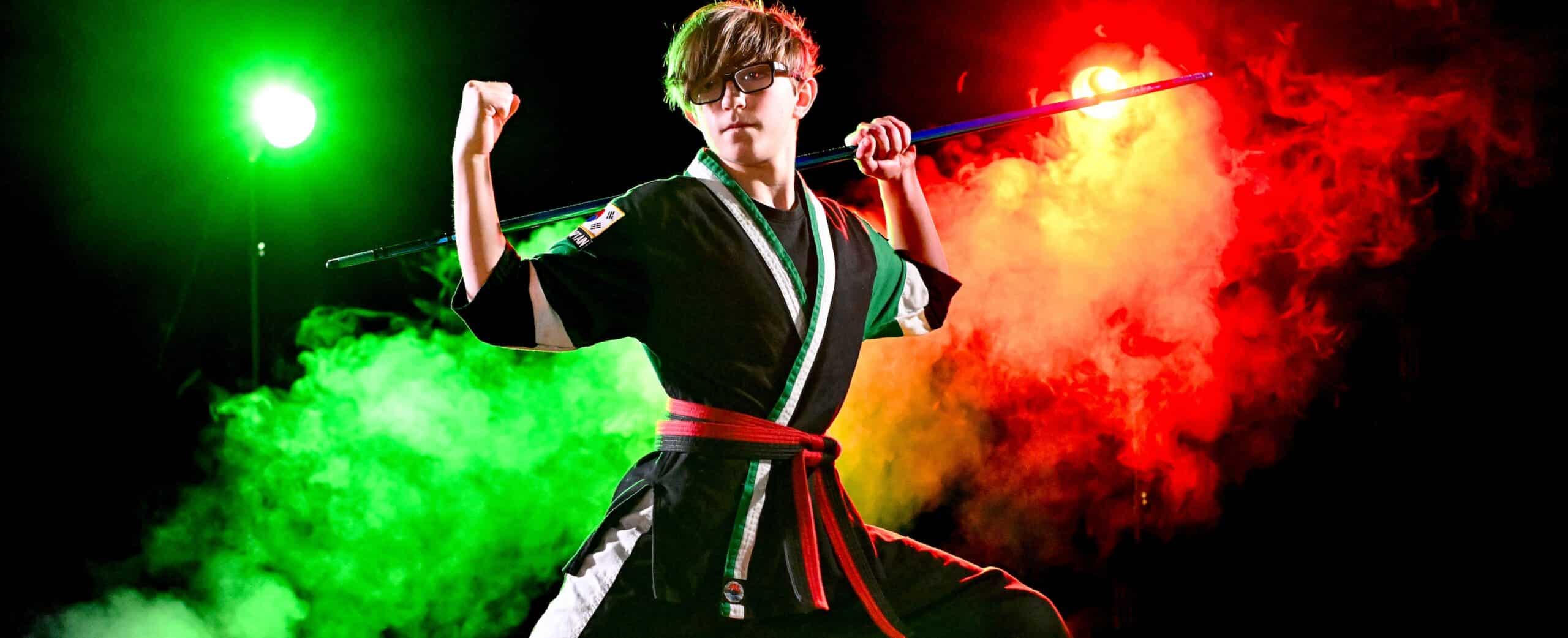 a student strikes a pose during his bo staff routine