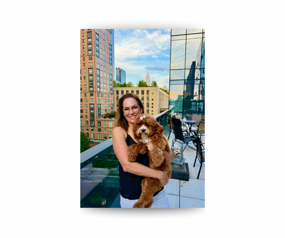 Alison holding Ruby on a rooftop terrace with the Empire State Building in the background.