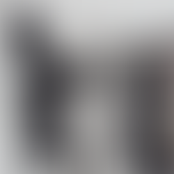 A woman browsing a rack of vintage and second-hand clothing in a boutique-style shop. She is viewed from behind while looking through curated pieces displayed on hangers.