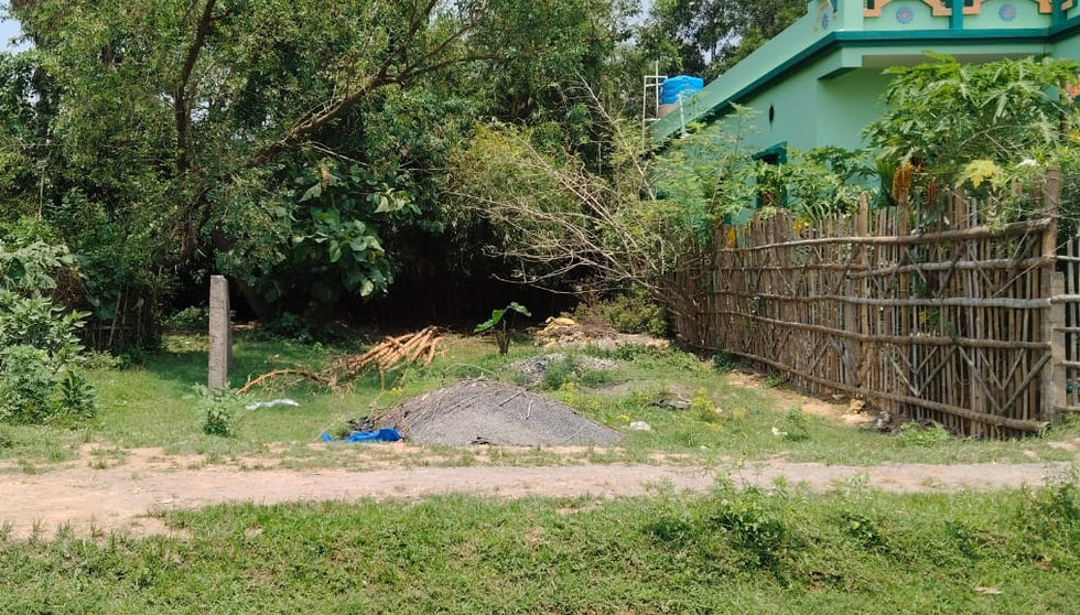 A pile of construction material near trees and a green house.