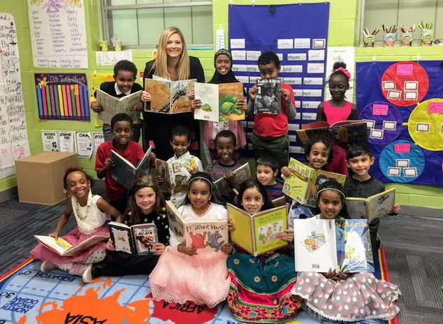 students and teacher posing with books