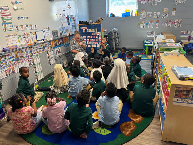 students sitting on classroom floor listening to teacher