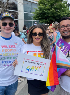 A group of people at a Pride parade. Demi is holding a sign that reads, "In Illinois, we say GAY!"