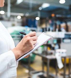 Young happy female worker in factory writing notes about water bottles or gallons before s
