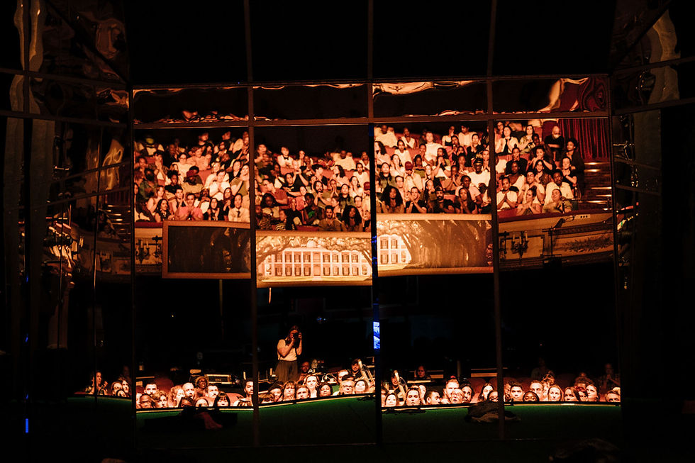 A theatre stage with a backdrop of mirrors reflecting the audience