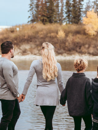 Family holding hand facing a river